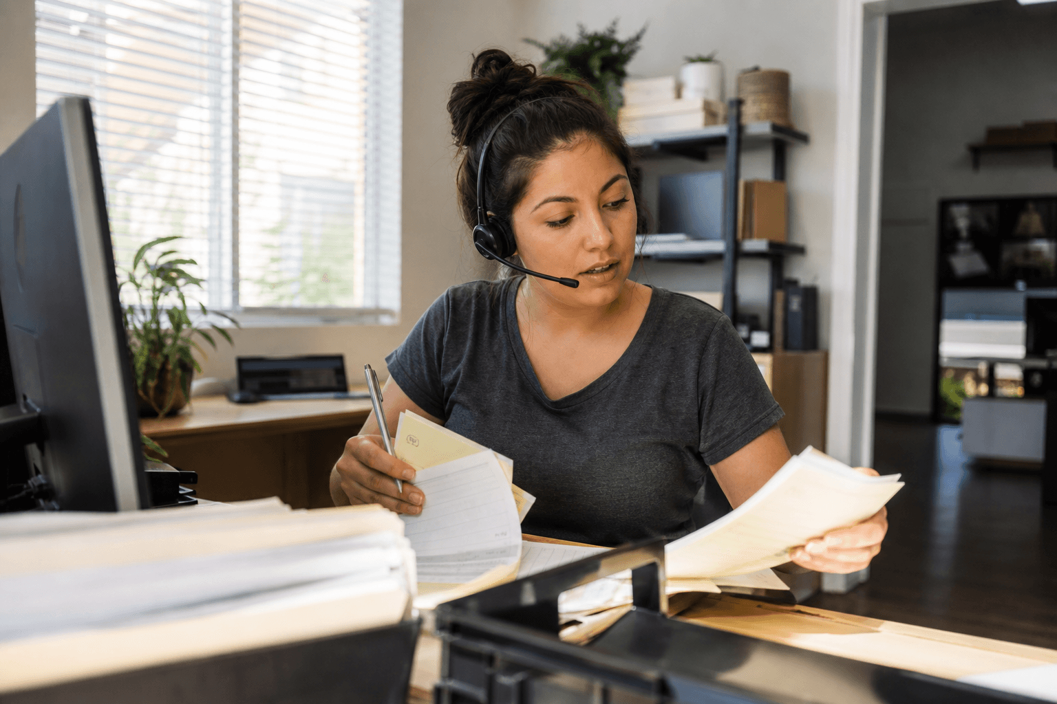 Office coordinator answering a customer call in a small service-company office